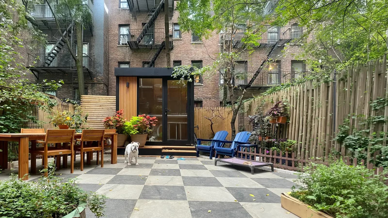 Black Autonomous MetroPod office installed in a small city courtyard between brick apartment buildings