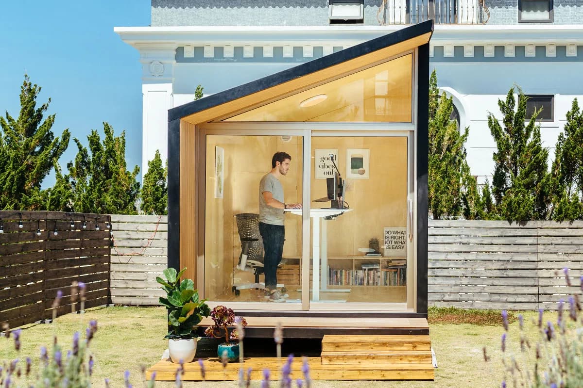 Person working at a standing desk inside an Autonomous WorkPod with full-height glass front