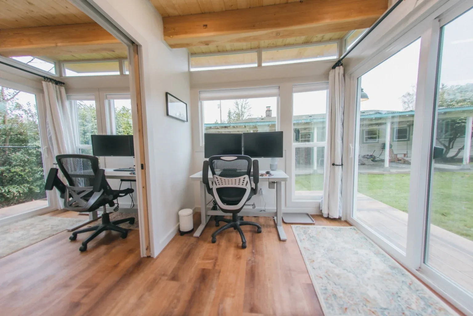 Two-desk home office interior of a Modern Shed with transom windows, wood ceiling, and glass doors