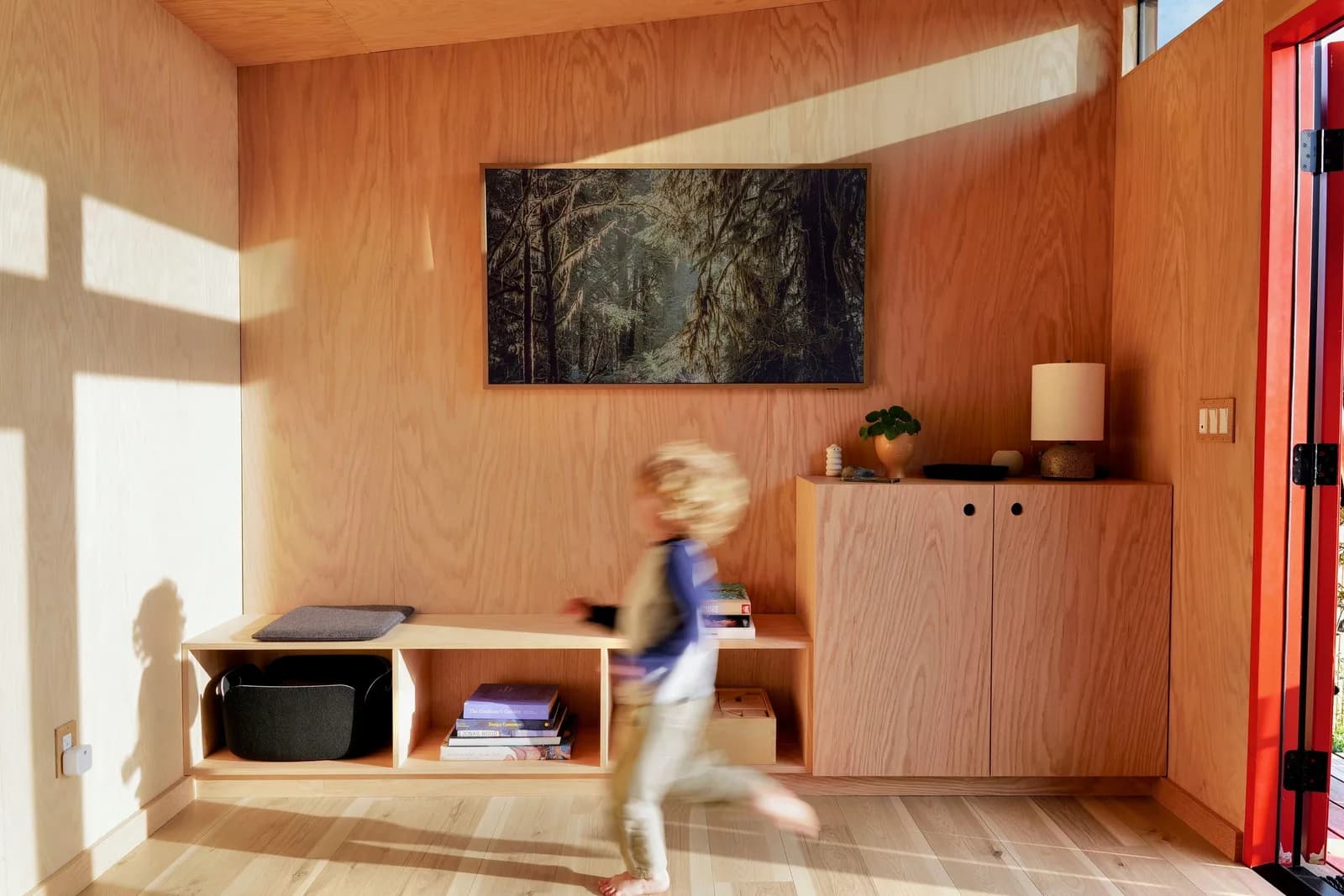 Plywood-lined interior of a 10x12 Studio Home Signature studio with built-in bench and red door