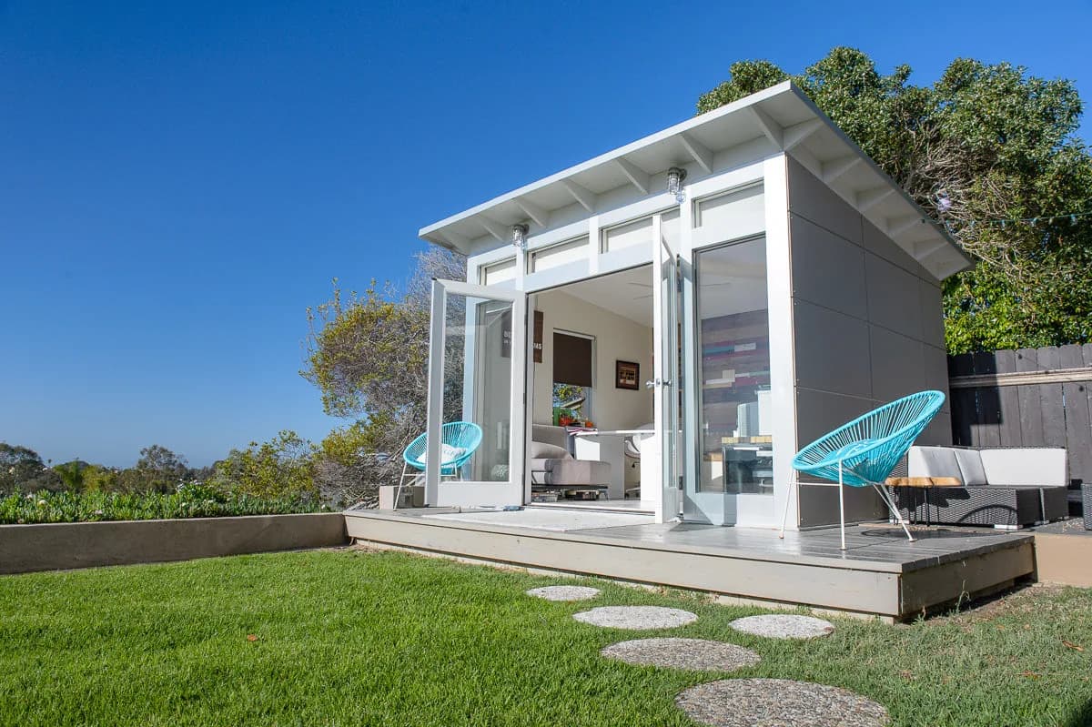 White Studio Home Signature backyard studio with open French doors on a gray deck overlooking a hillside